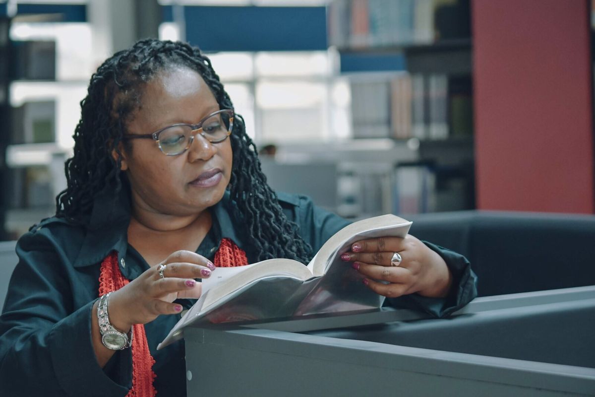 Lucy Mulli reading at a library table